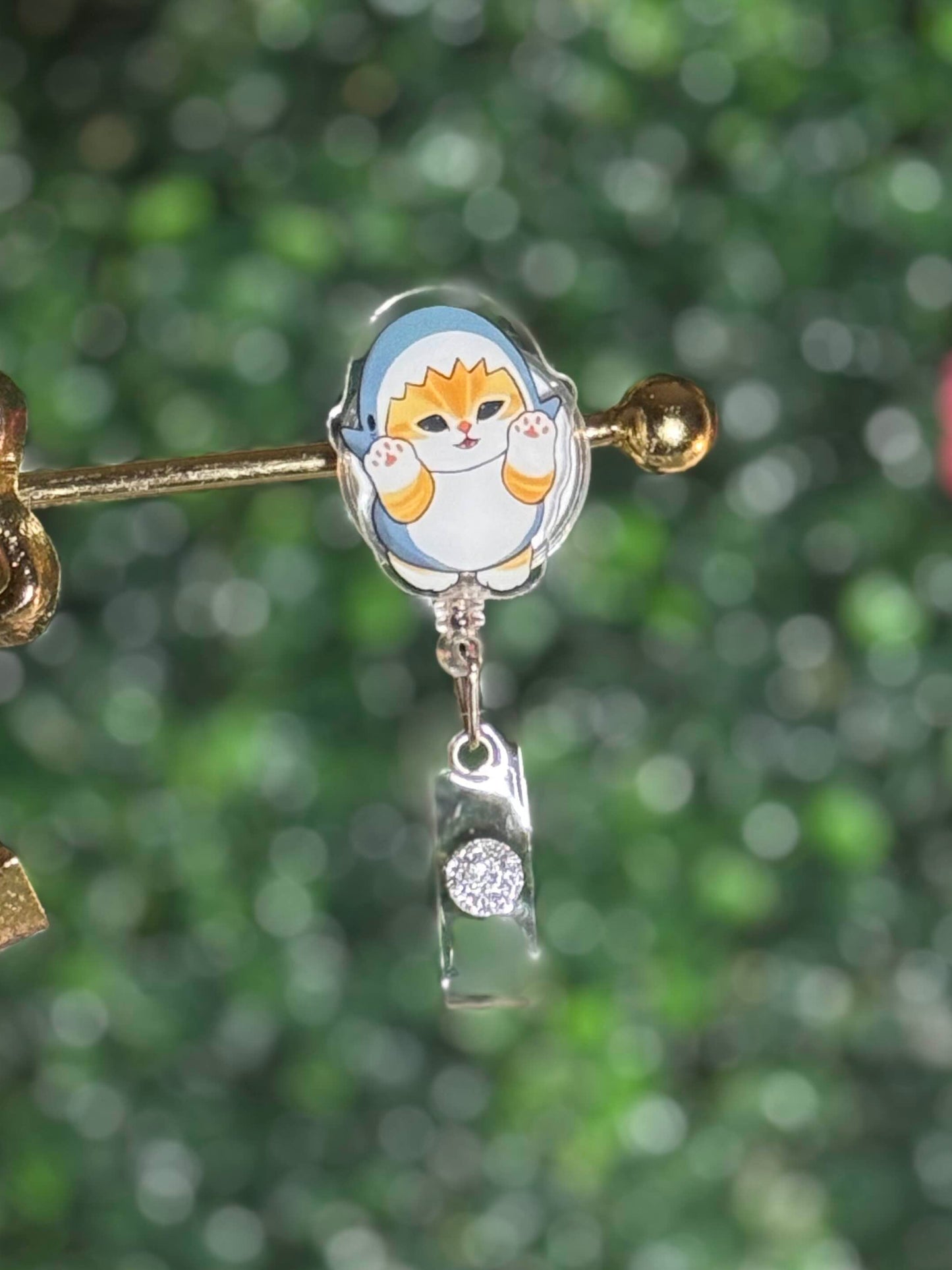 Decorative brooch with cartoon character and bow detail on a blurred green background